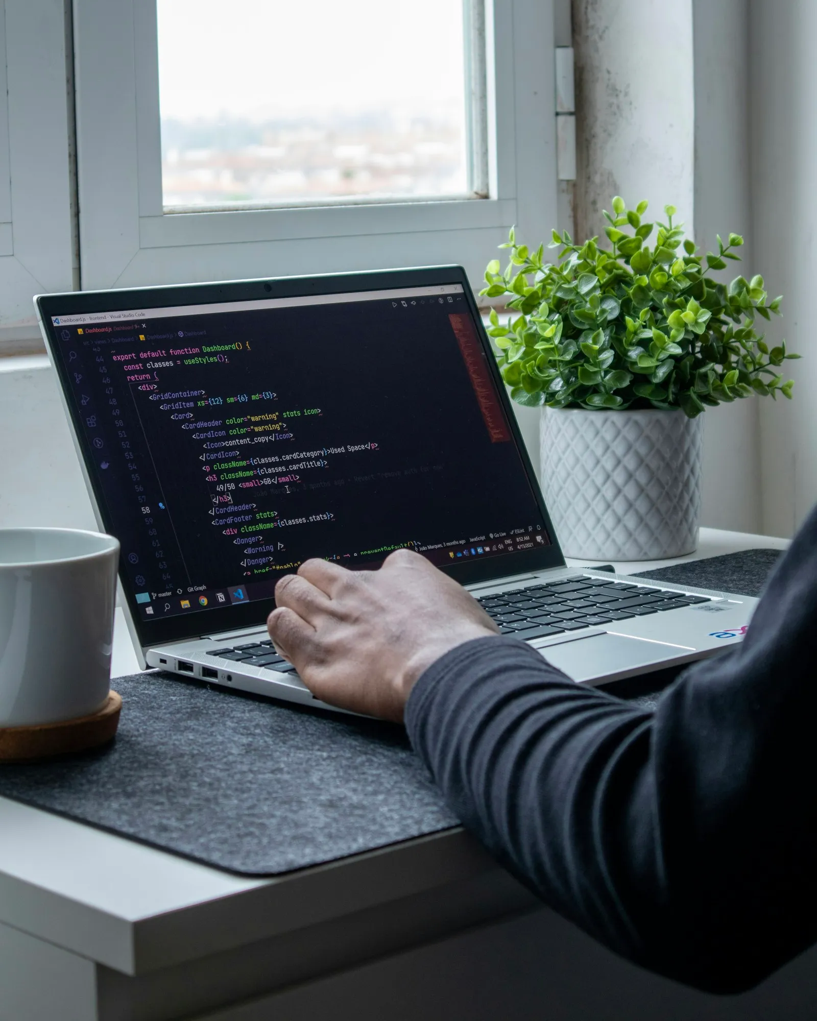 A developer typing on a laptop with code on the screen